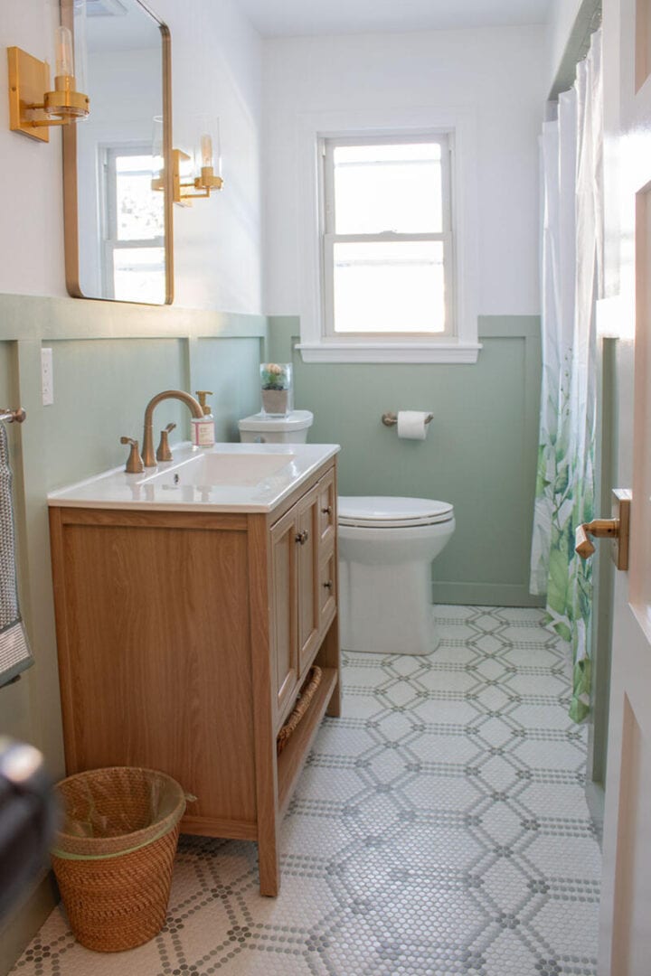 green-bathroom-with-wood-vanity-and-brass-accnets